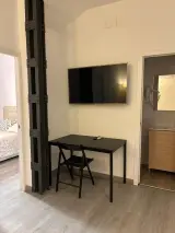 Pilar de metal negro en la zona de estar del Apartamento Exterior con vista a la cama y al muro de ladrillo del dormitorio